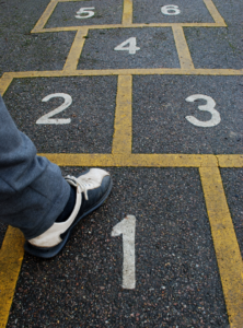 A person's feet on a hopscotch board.